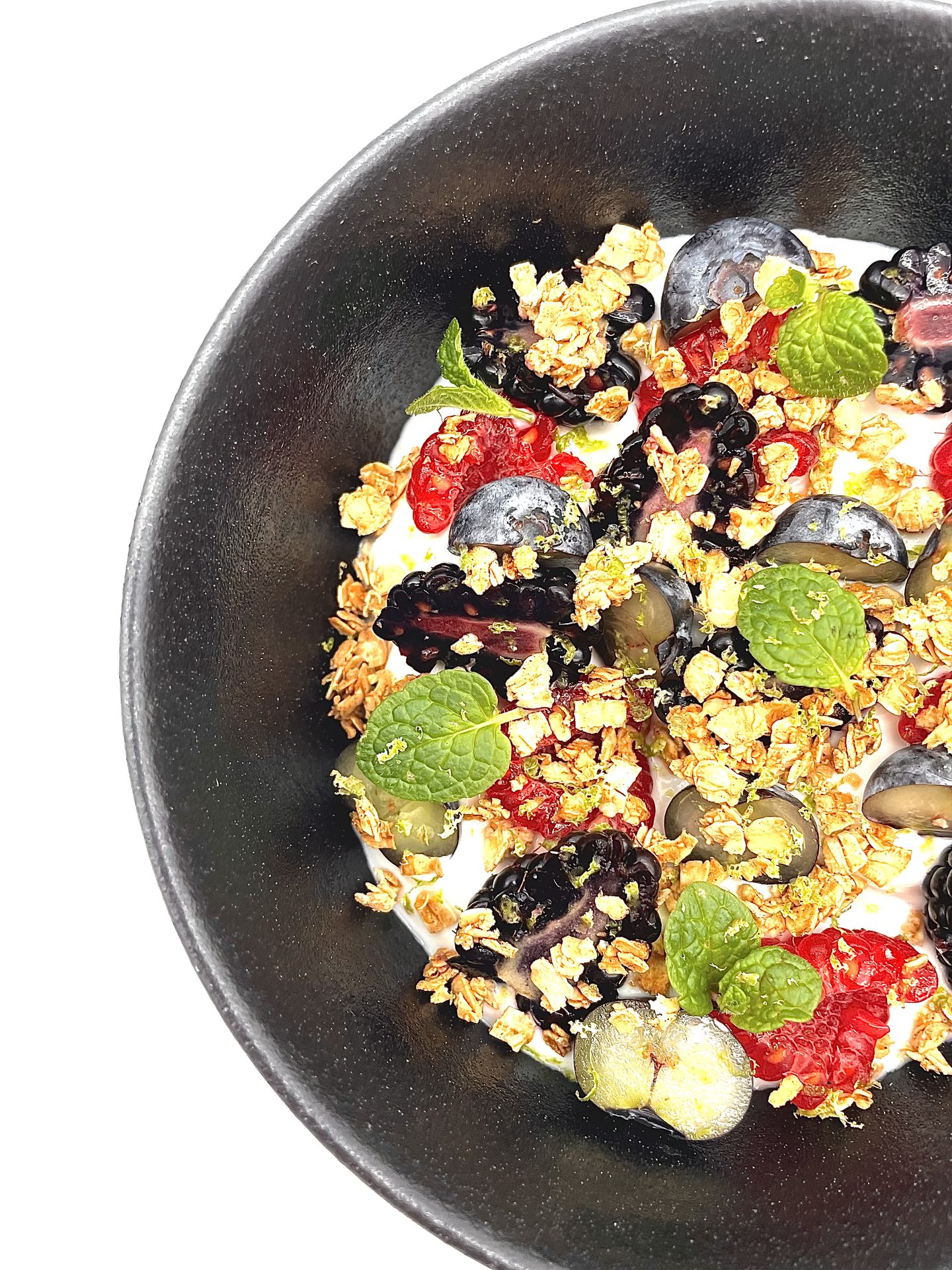 Granola with fresh berries and herbs in a dark bowl