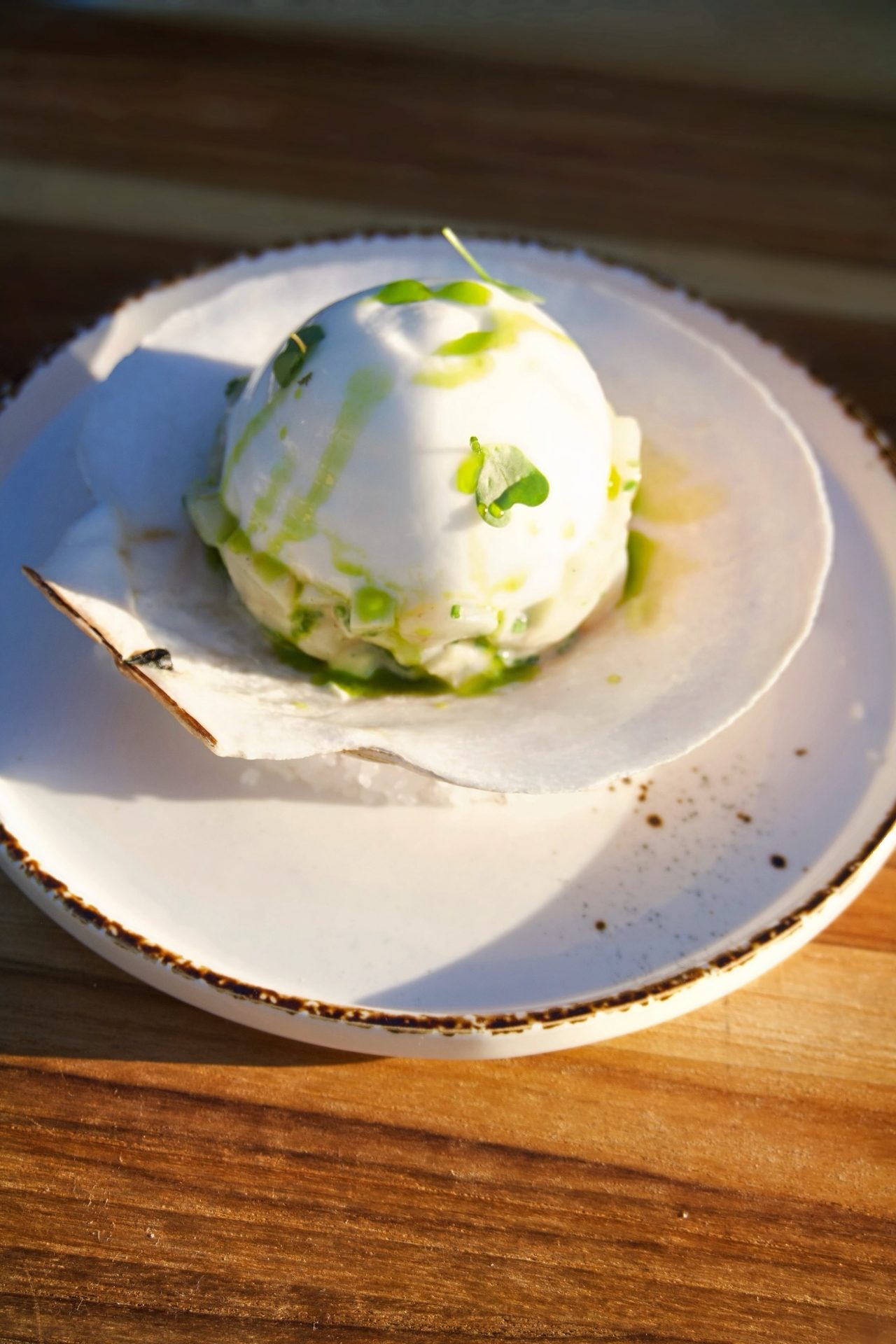 Burrata with herb oil served on a wooden board