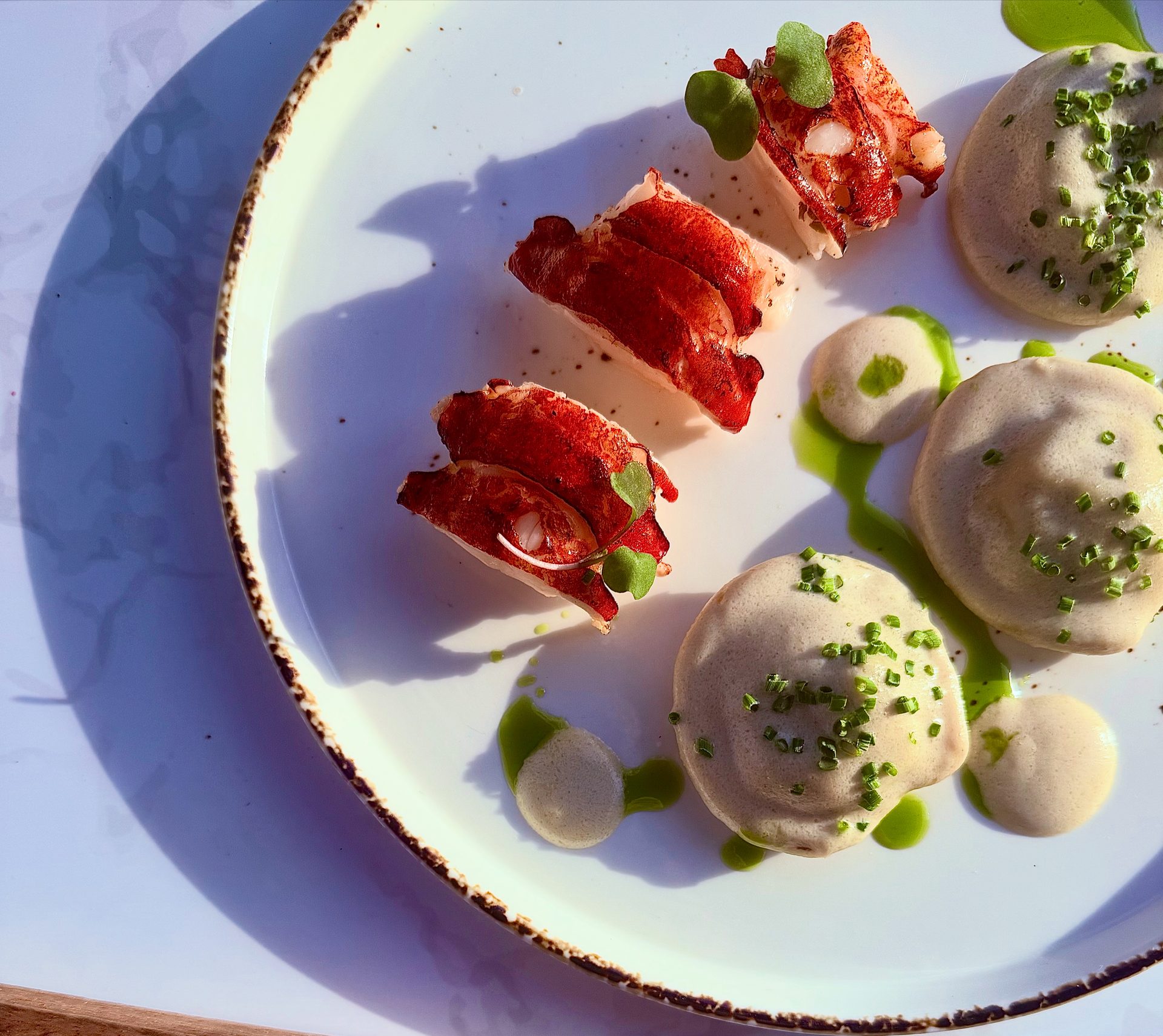Plated course of tomato with quenelles and herb oil