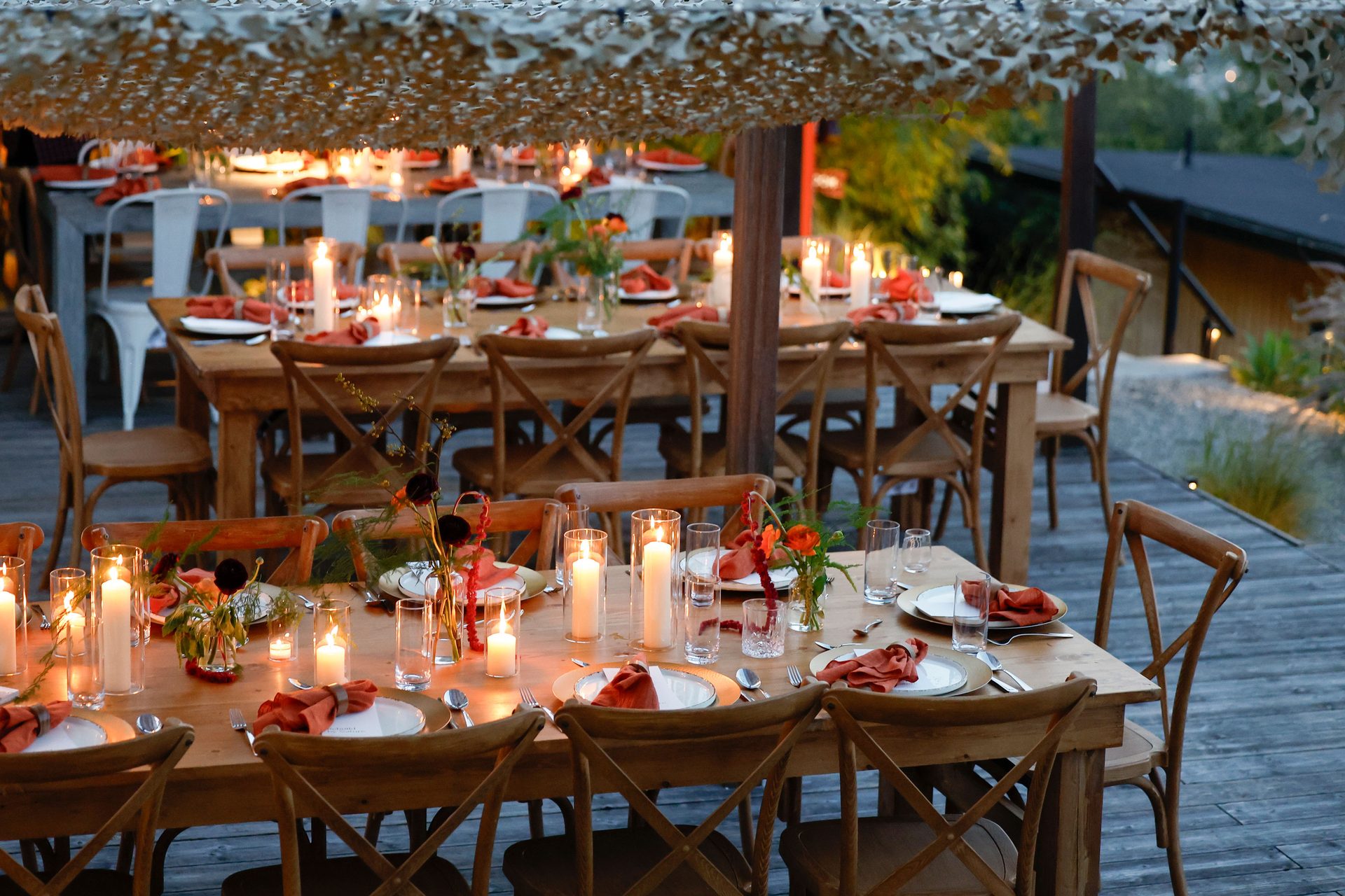 Outdoor dining table set with candles and flowers at dusk