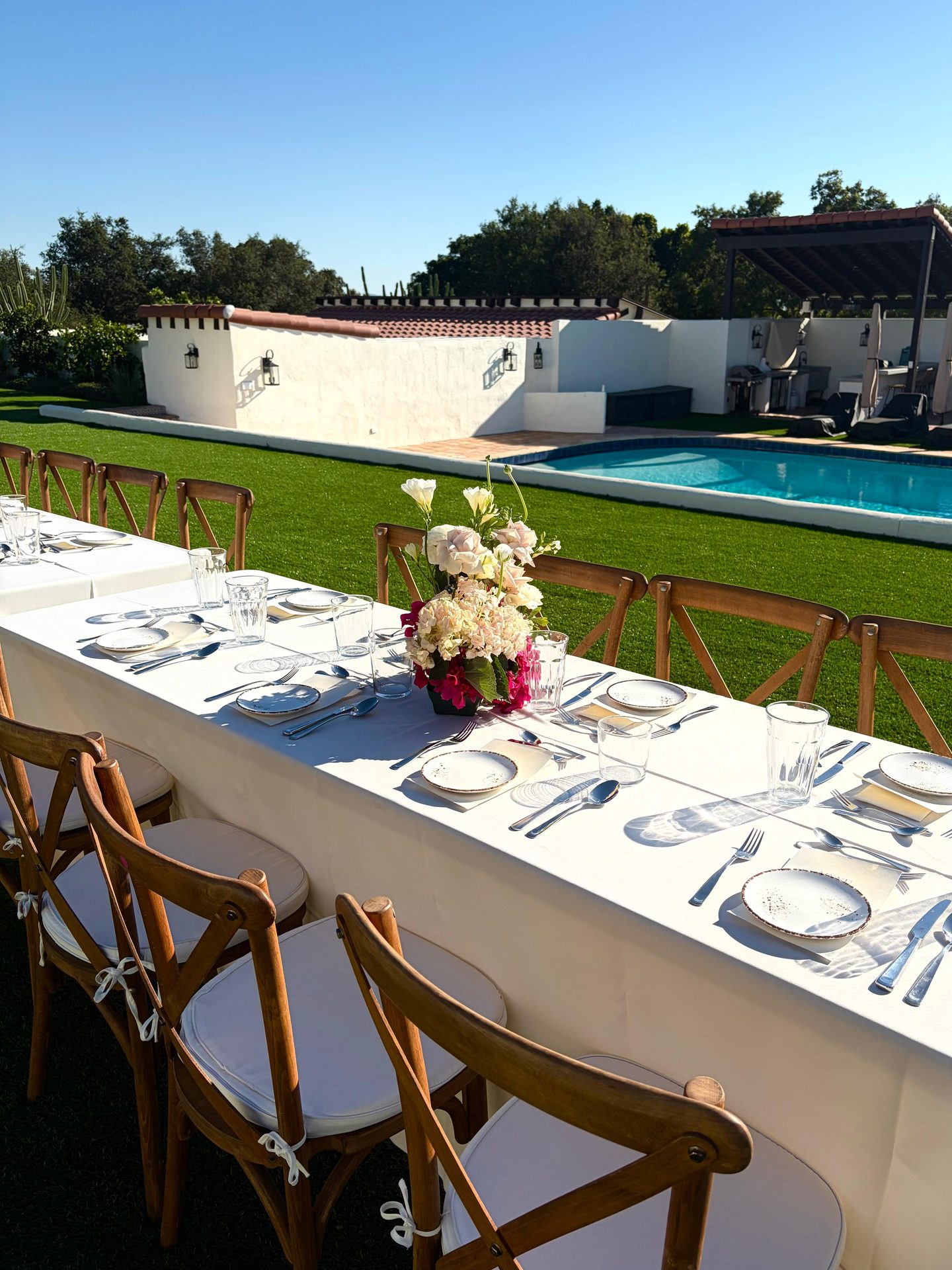 Long banquet table set for a poolside private dinner