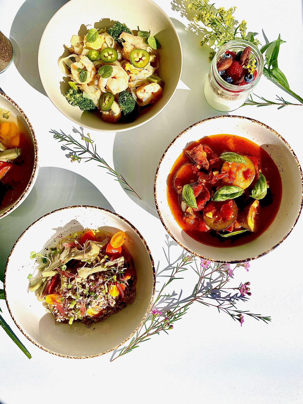 Prepared bowls of grain salad, braised vegetables and a parfait