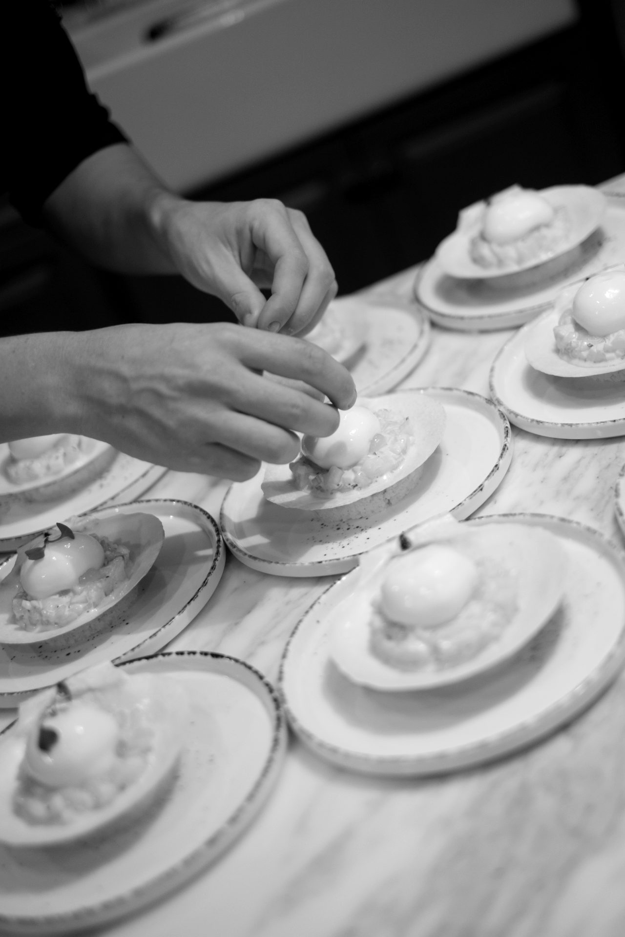 Hands placing canapes onto individual serving dishes