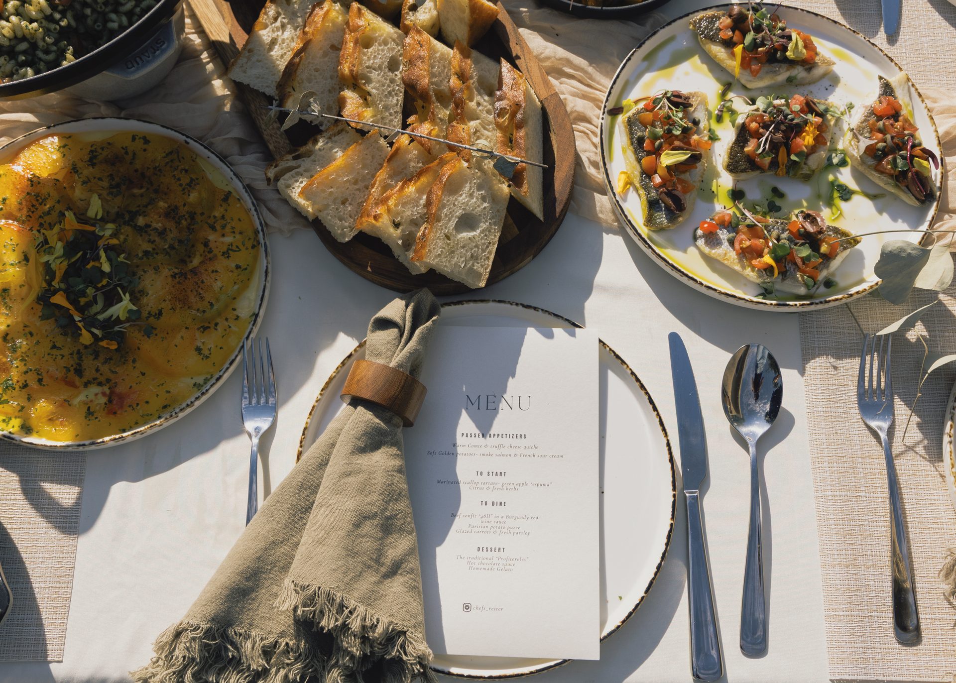 Plated tasting courses laid out on a linen table beside a printed menu